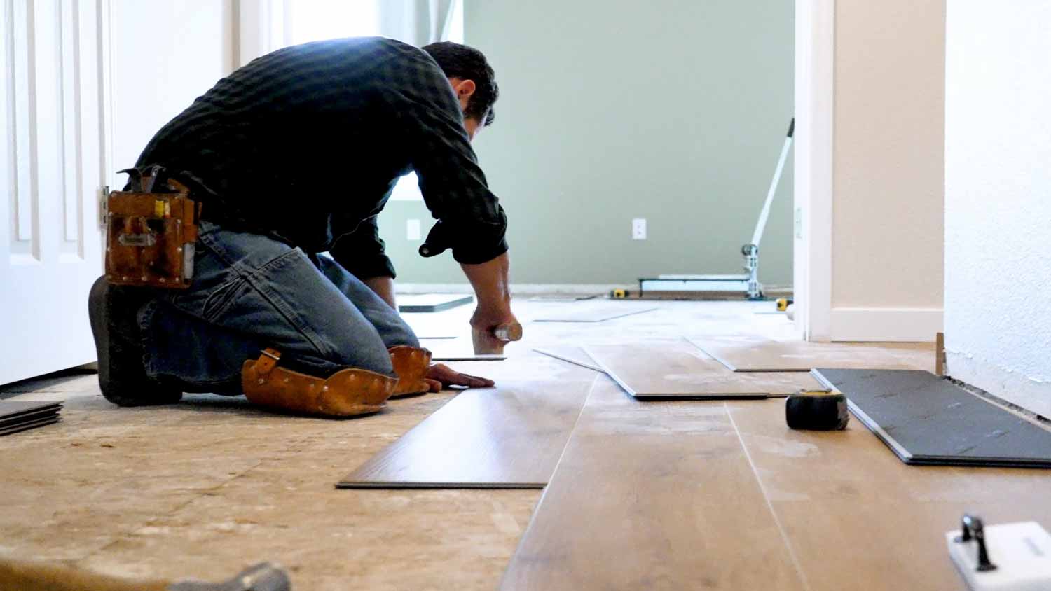 Worker installing wooden vinyl floor 