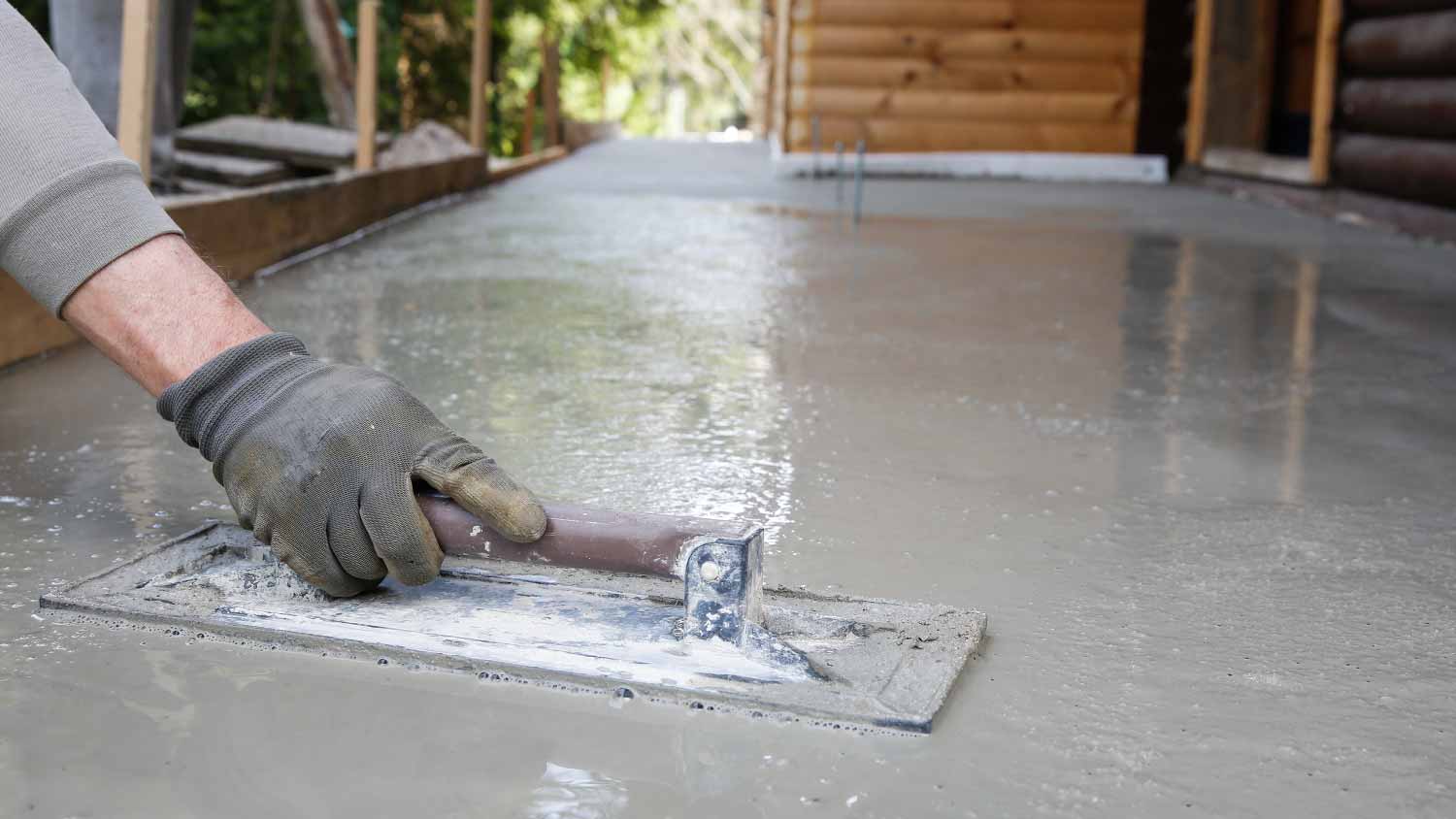 Worker leveling and screeding concrete floor  