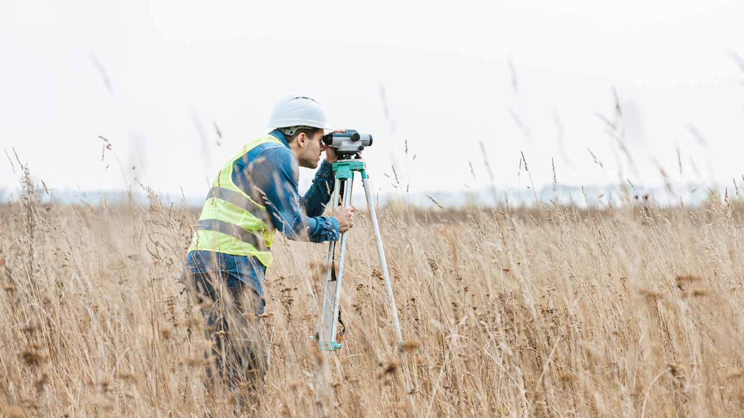 Worker measuring field with digital level