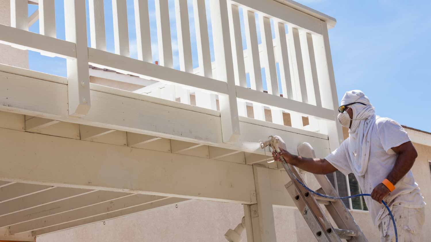 Worker painting a deck of a home