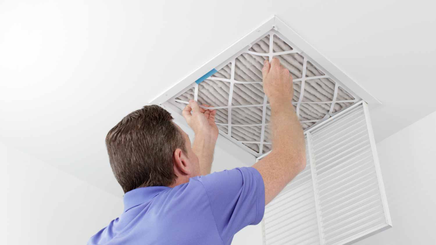 Worker removing ceiling air filter 