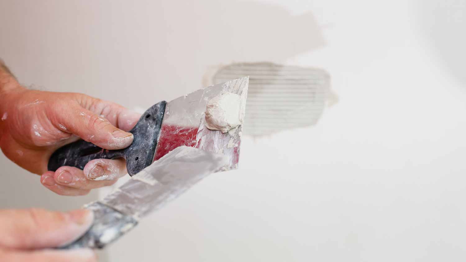 Worker repairing a hole in drywall