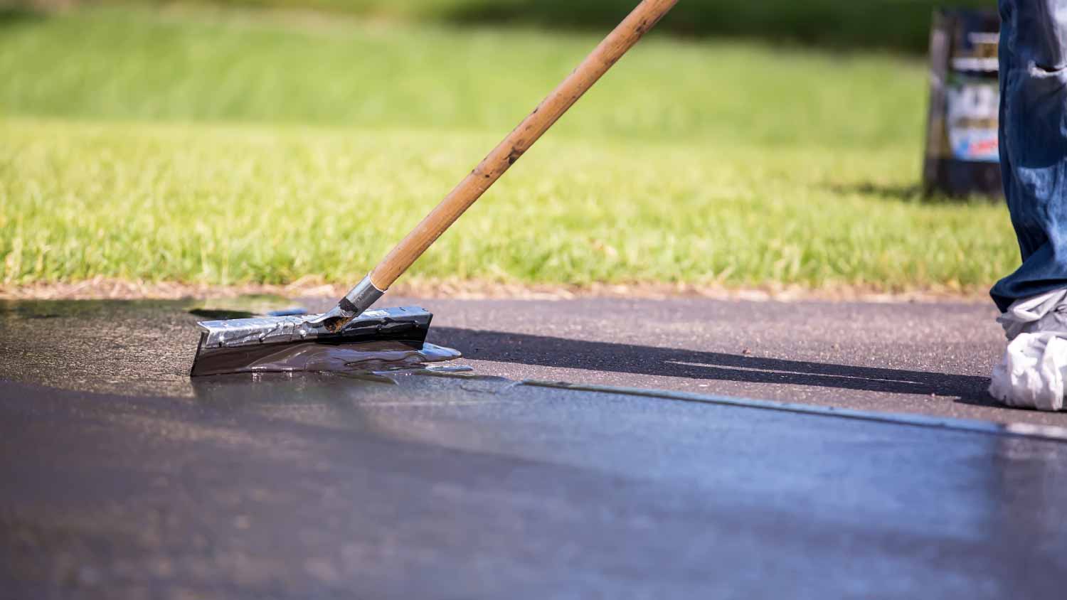 Worker seal coating a driveway