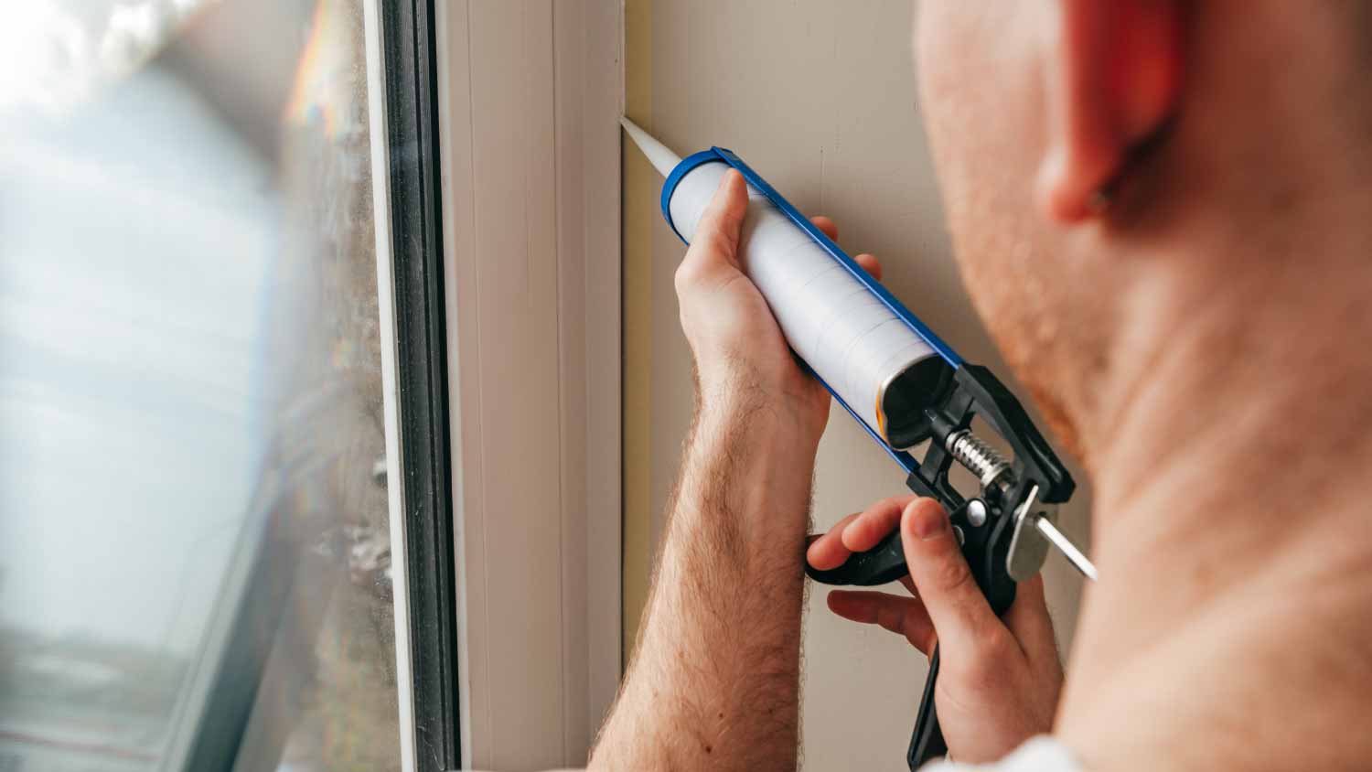 Worker sealing cracks between window and trim