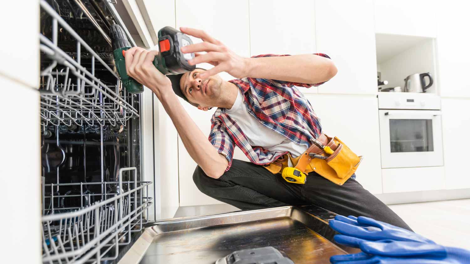 Worker using screwdriver to repair dishwasher 