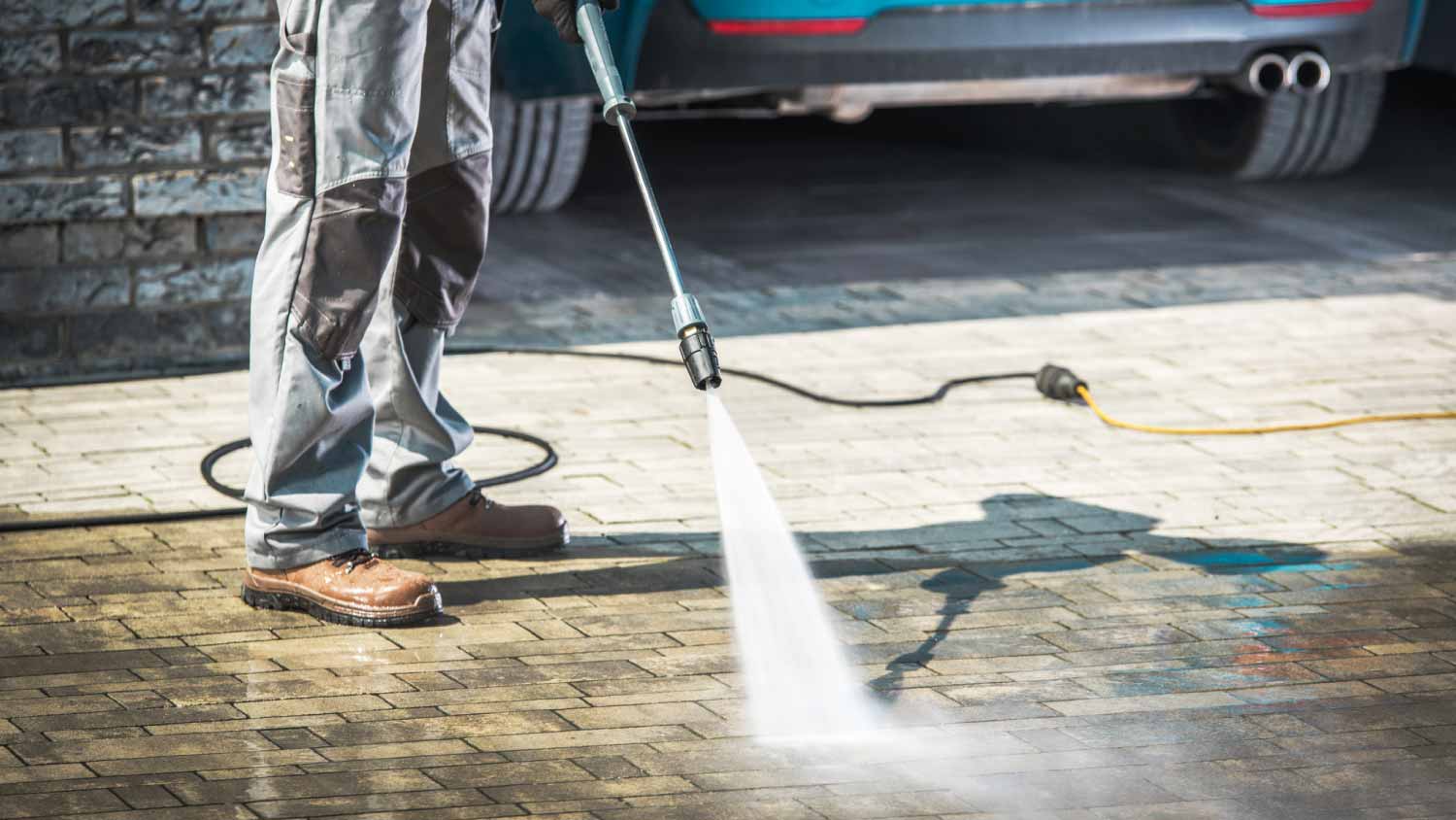 Worker washing driveway