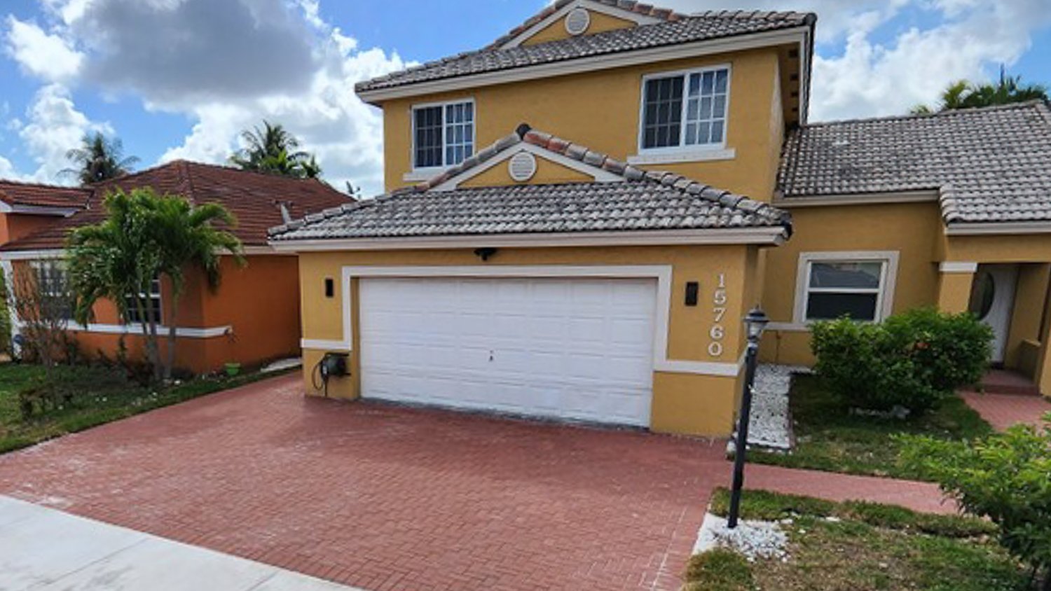 Yellow house with red brick driveway