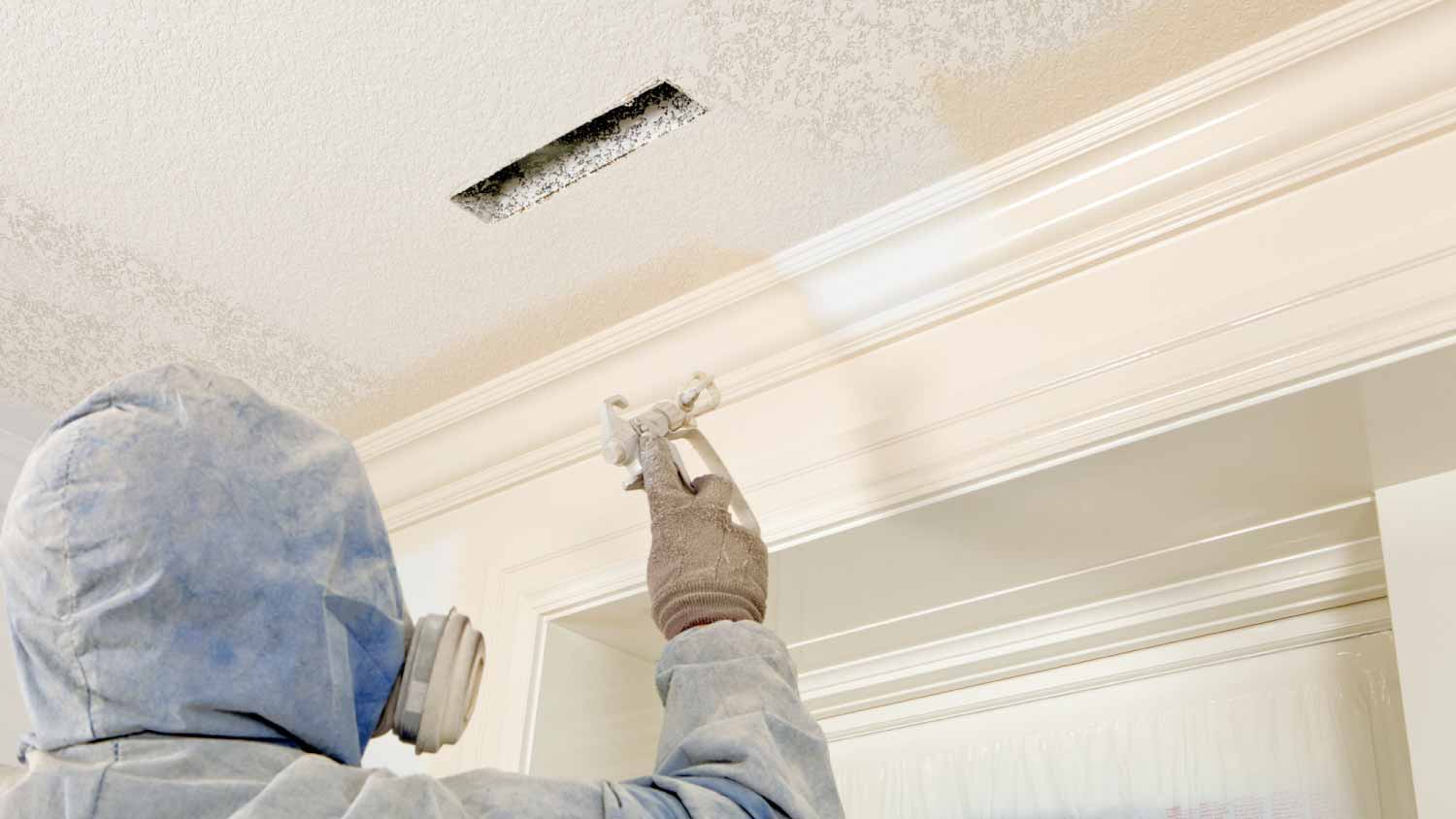 Painter spraying paint on crown moulding