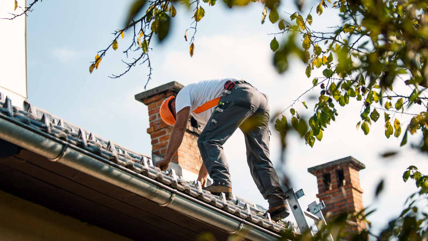 Roofer measuring chimney on rooftop