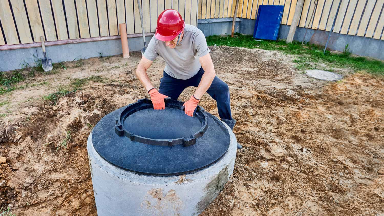 Worker installing fiberglass support ring under manhole cover