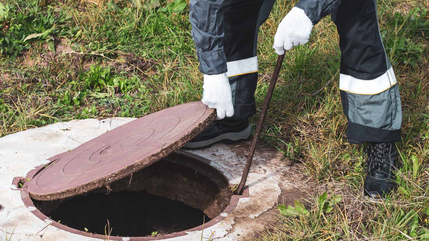 Worker opening septic tank cover