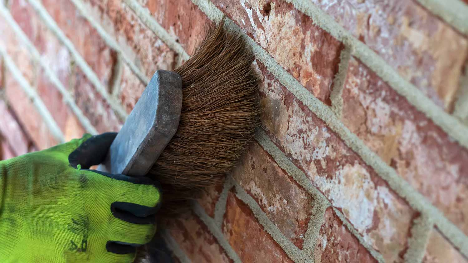 Man using bristle brush to clean brick