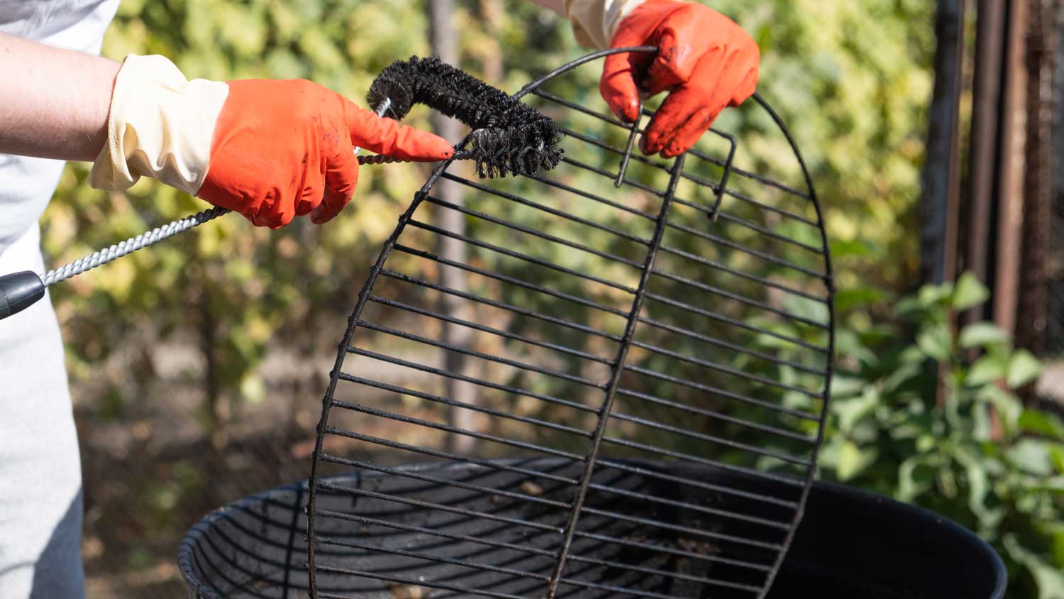 man cleaning grill with brush