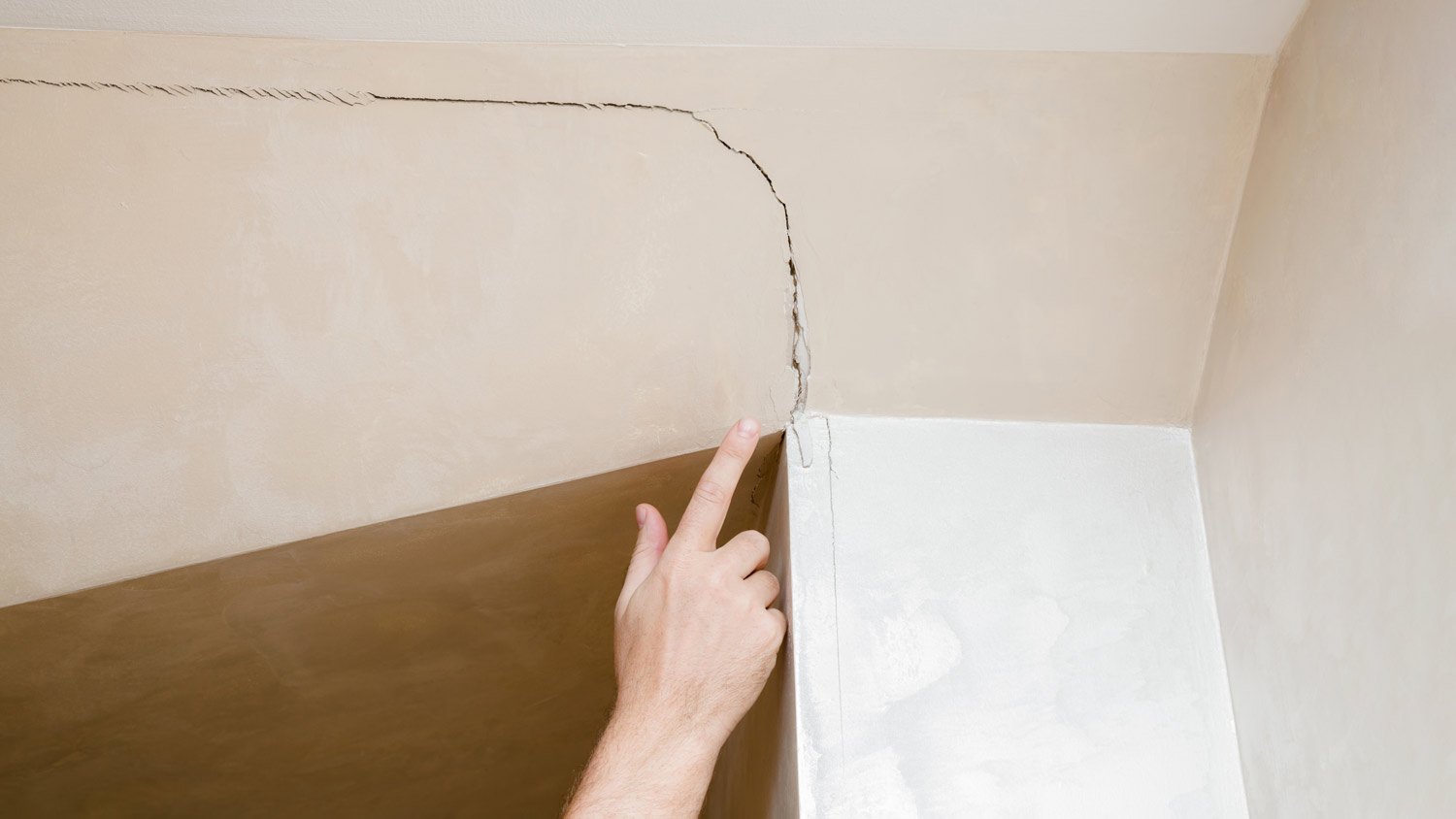 man pointing to crack in the wall