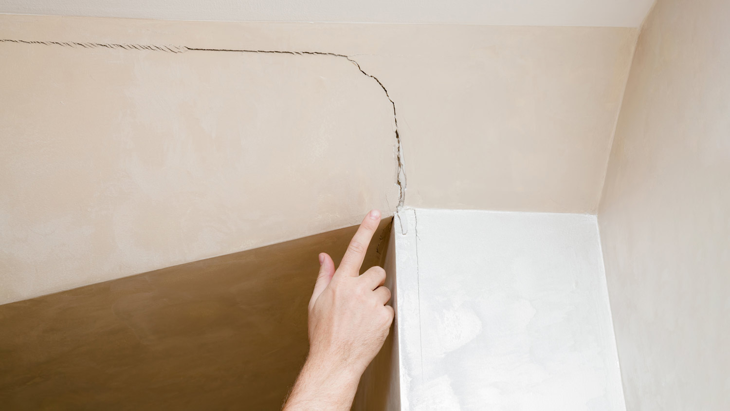 man pointing to crack in the wall
