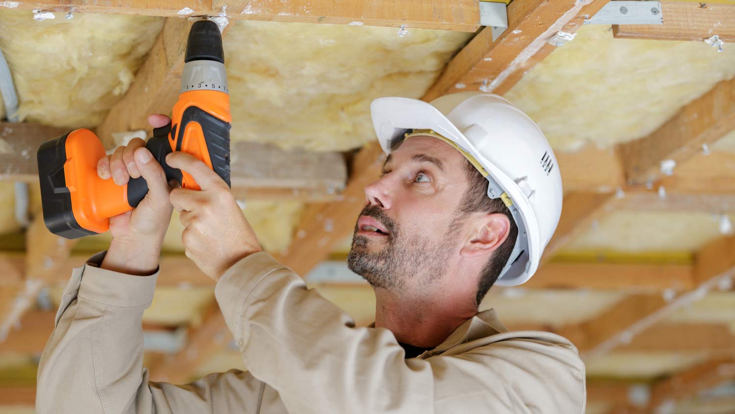 worker using drill on ceiling joist