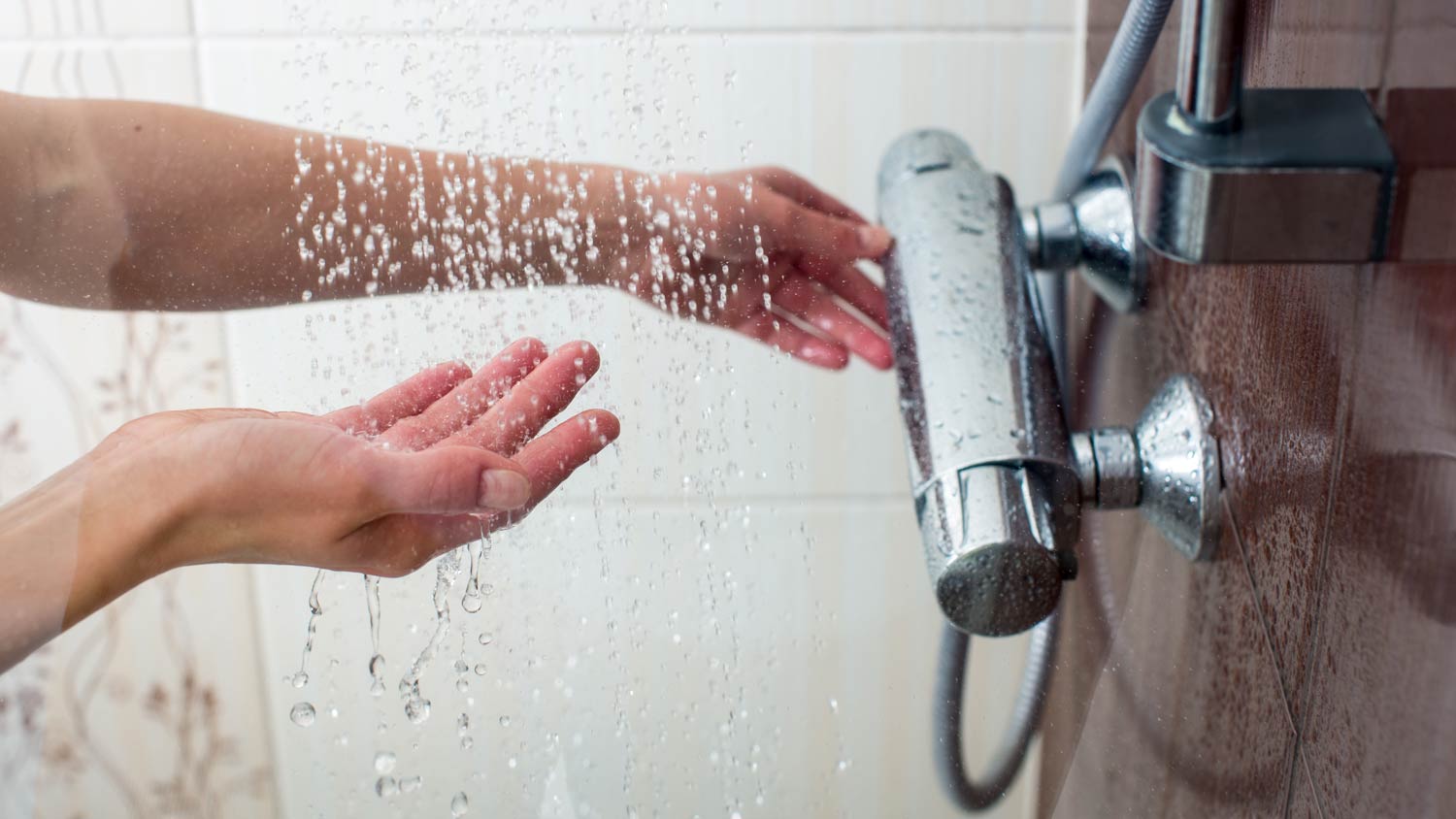 woman feeling temperature of shower
