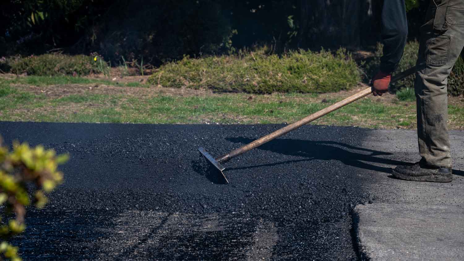 smoothing fresh asphalt on driveway