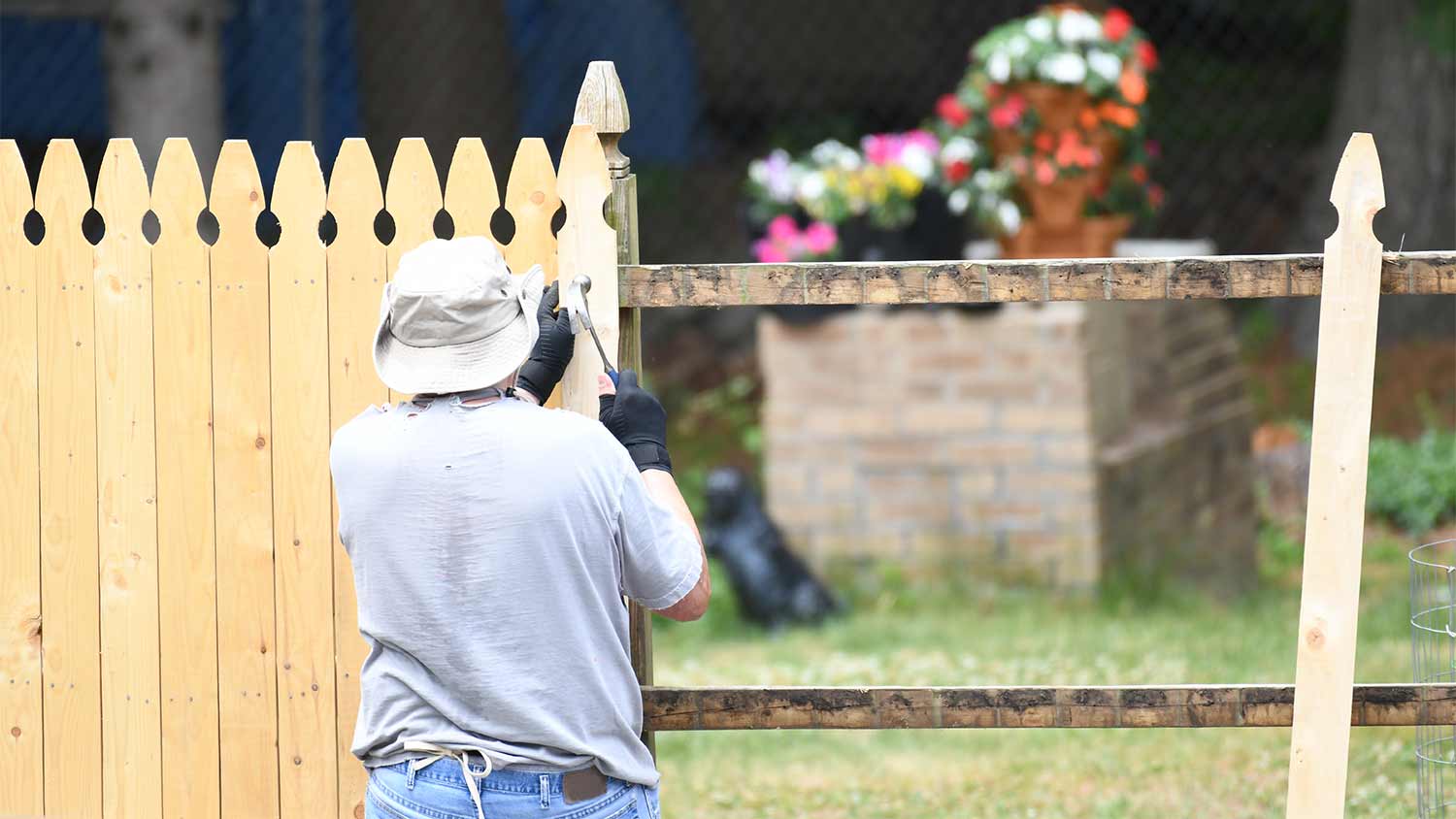 worker installing wood fence in yard