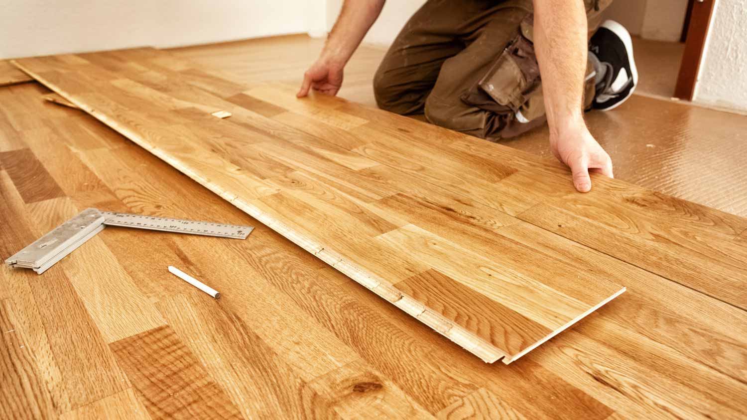 man laying down hardwood floor  