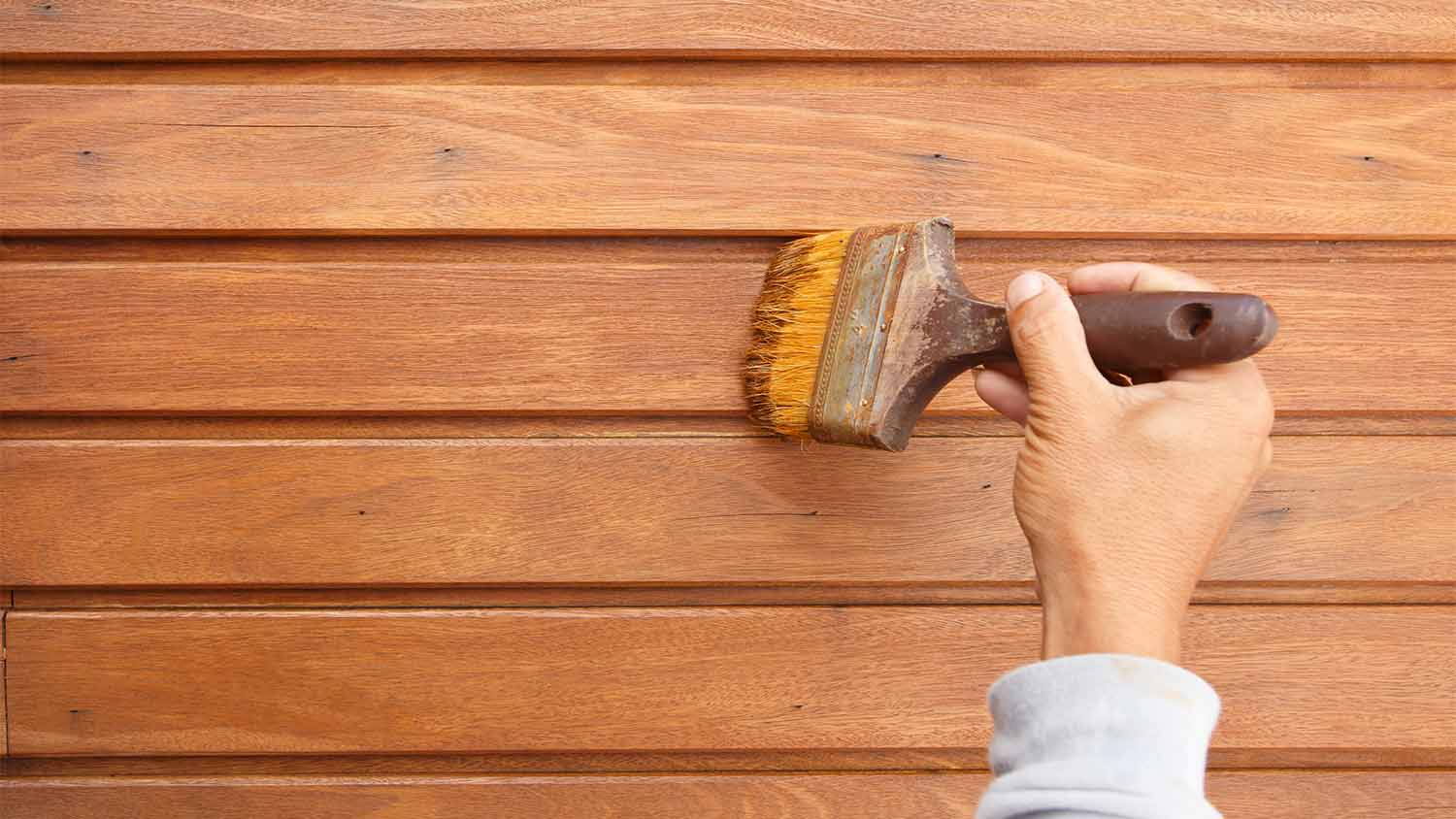 person painting wood siding