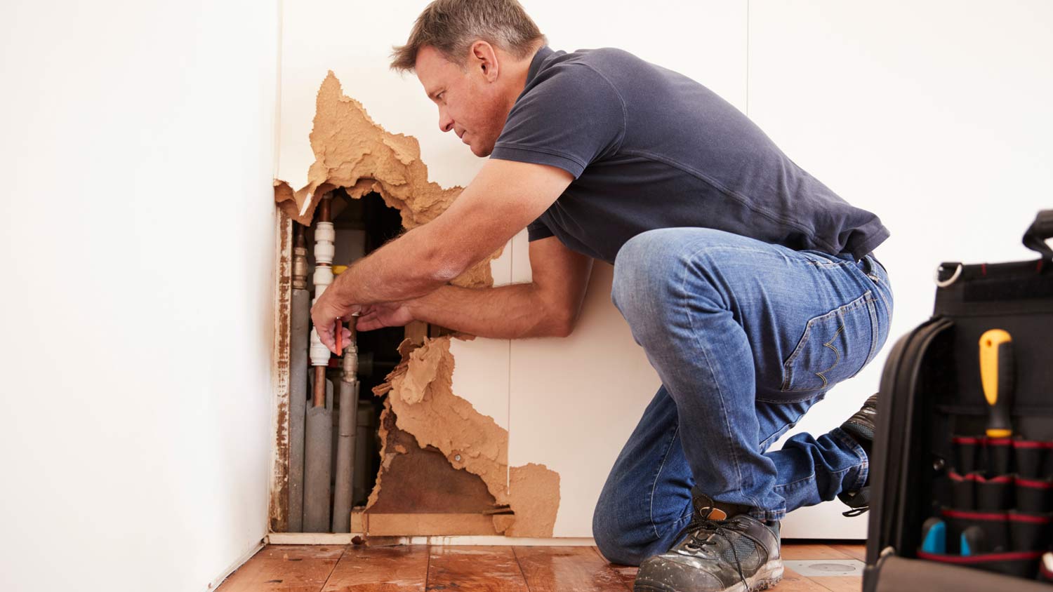 man repairing burst pipe