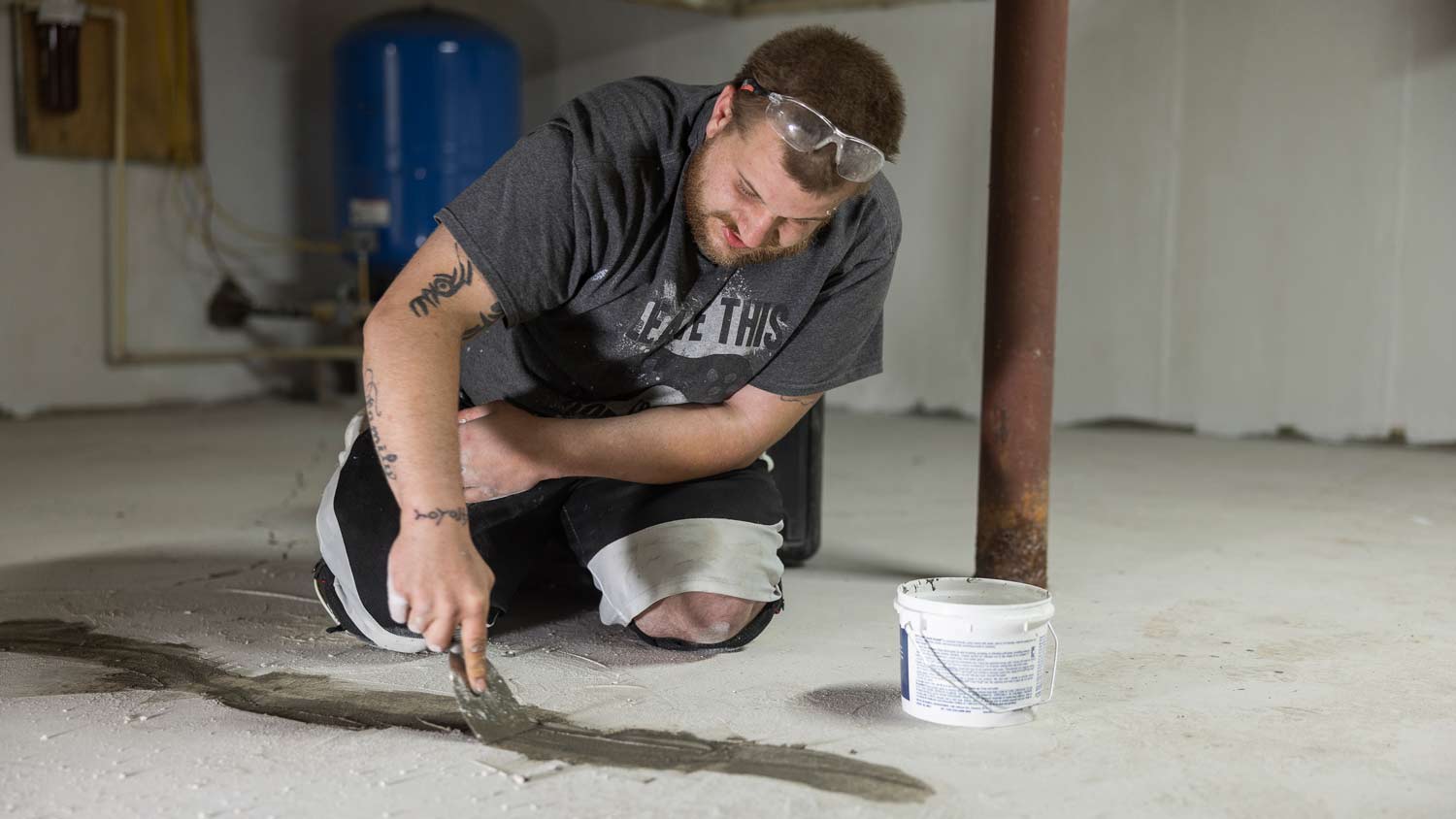 man sealing cracks in basement floor