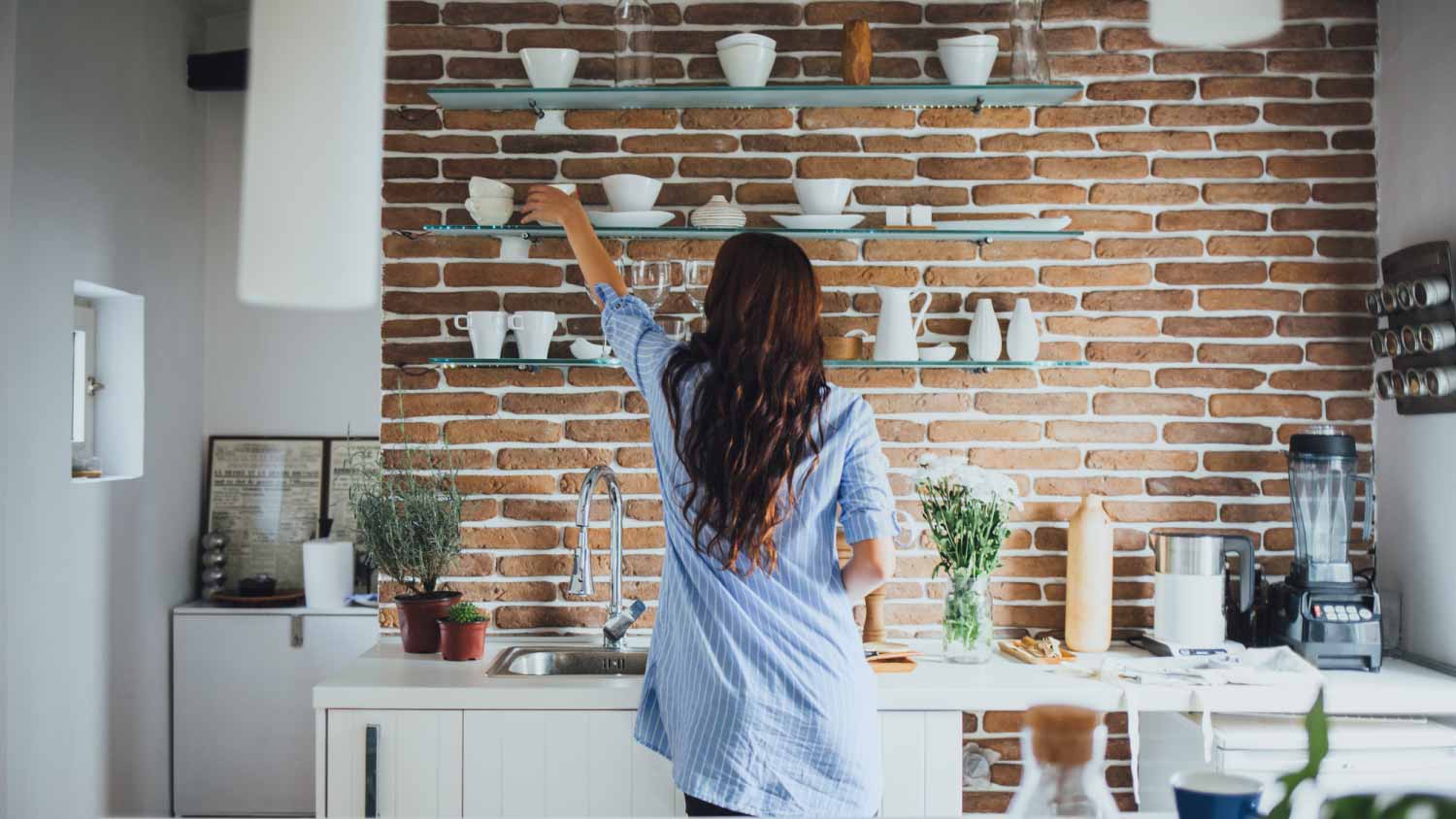 Woman reaching for dishes in kitchen