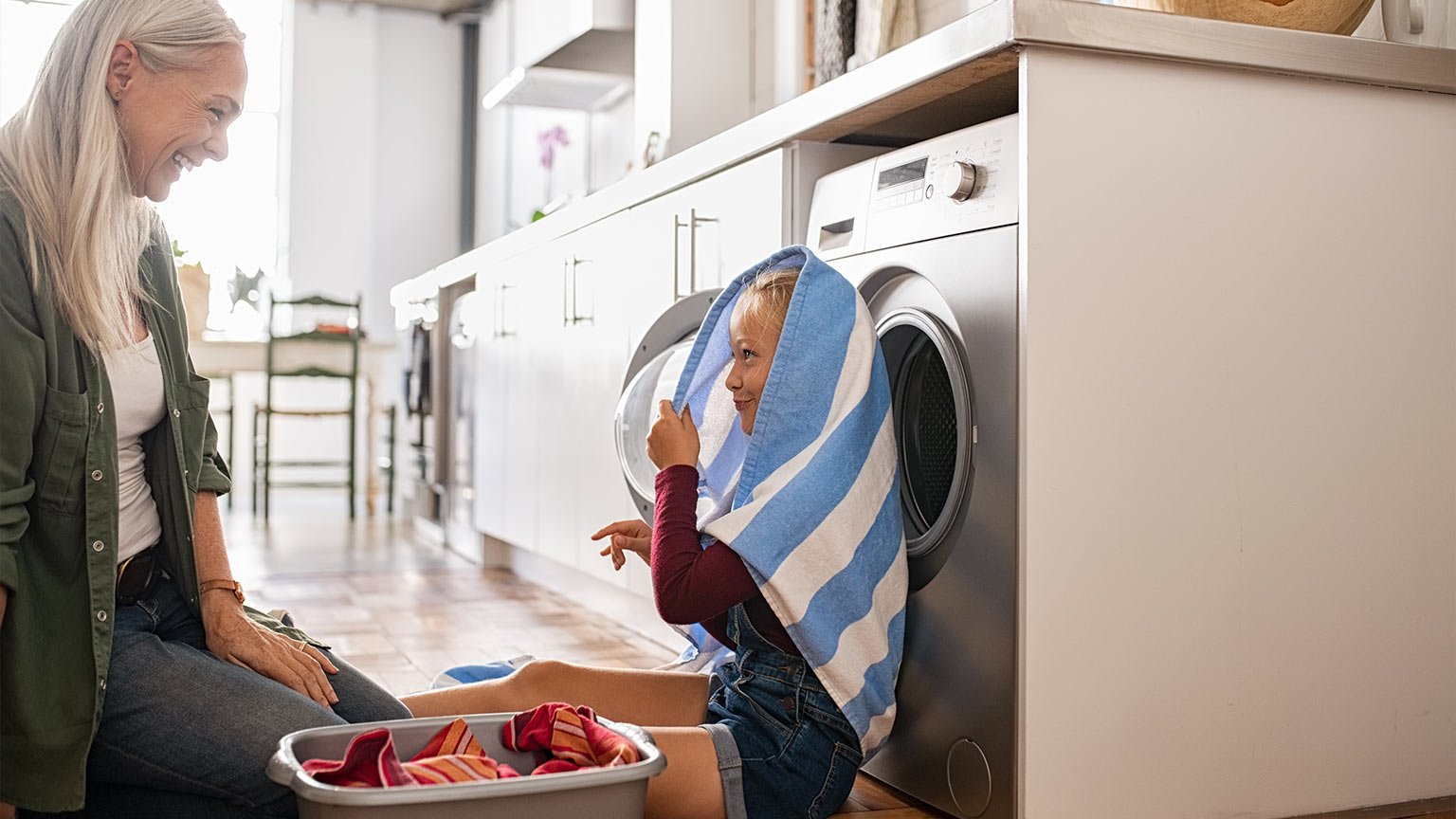 Mature woman and little granddaughter playing at home on laundry day