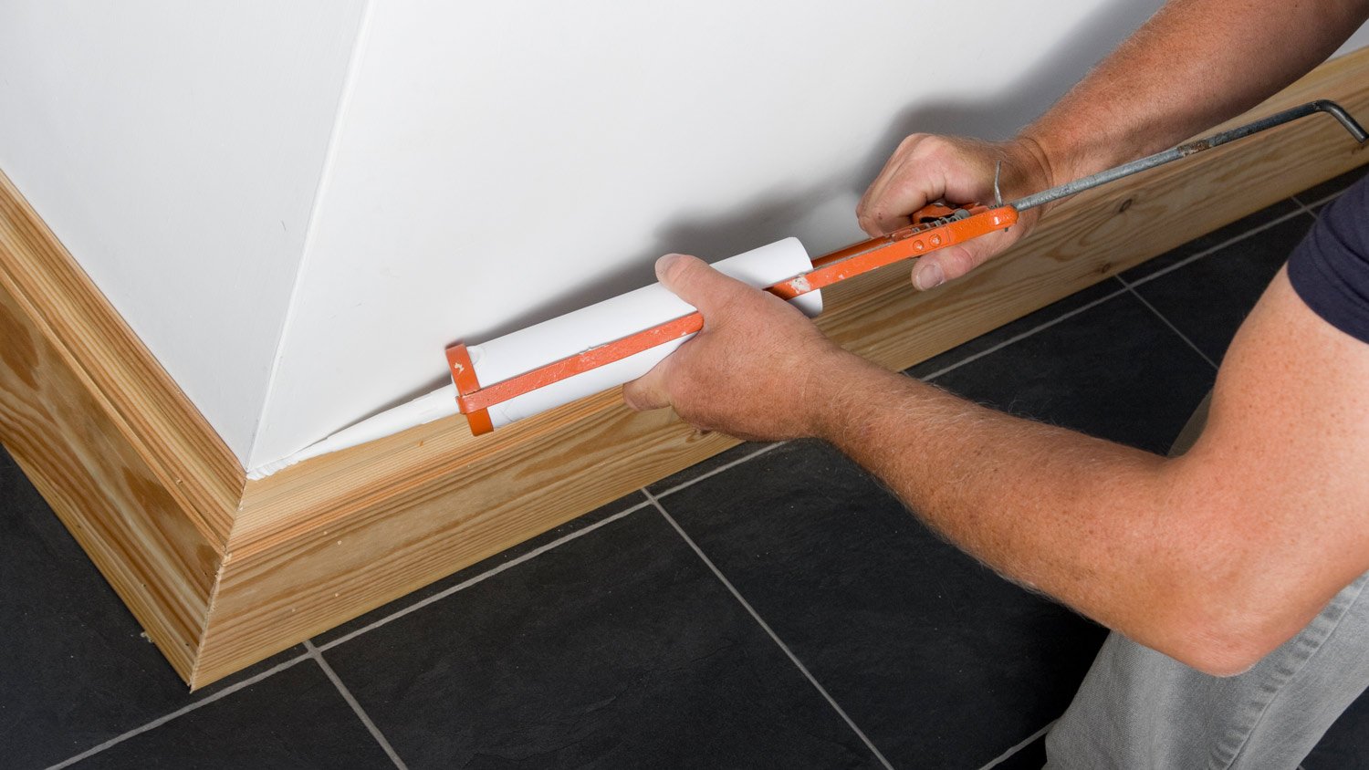 Man caulking wooden skirting in a new property