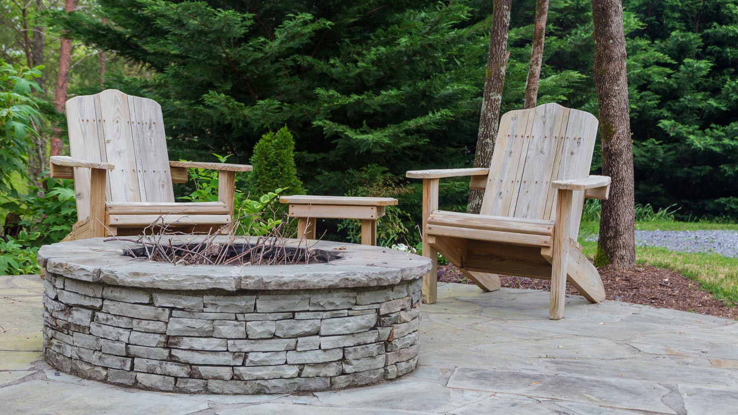 Adirondack chairs around a firepit in a house’s backyard