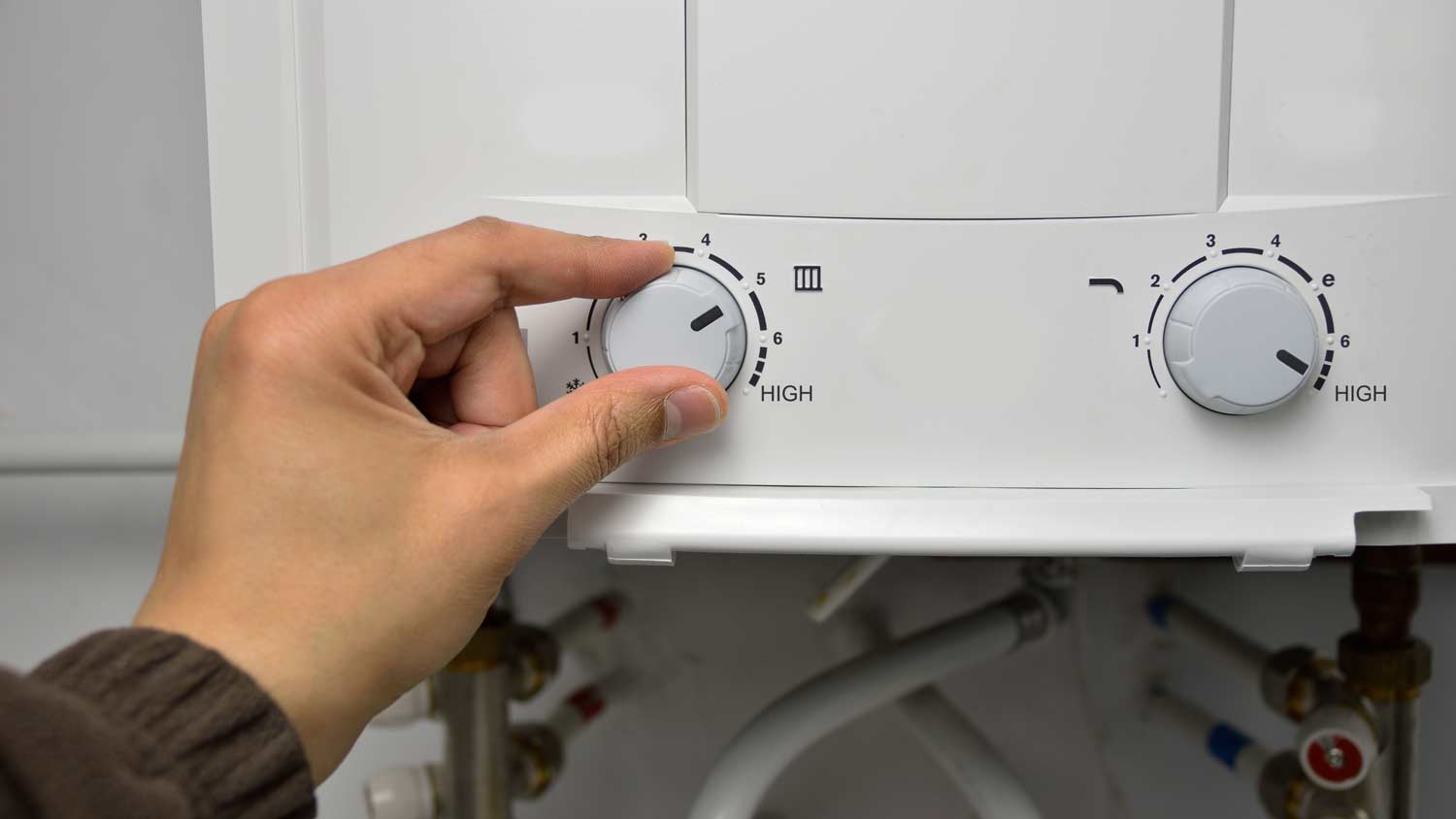 man adjusting temperature on water heater 