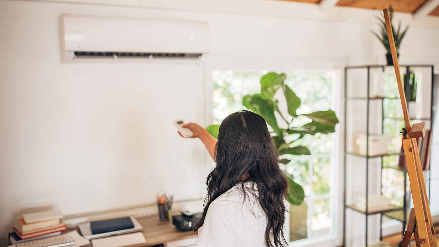 Woman adjusting ac temperature with a remote control