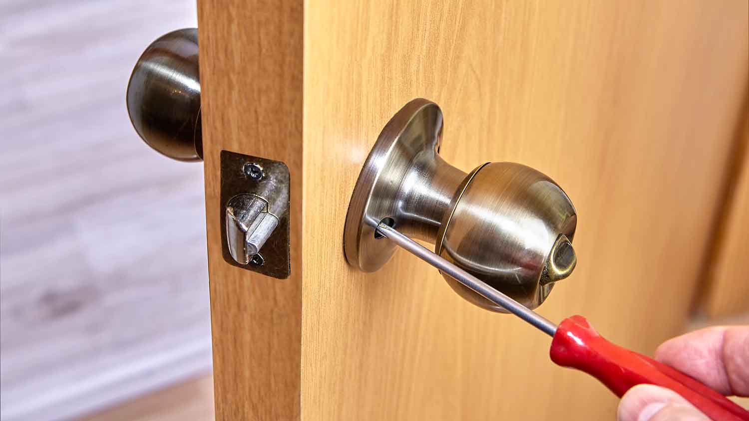 Person adjusting the screws connecting a handle to the door
