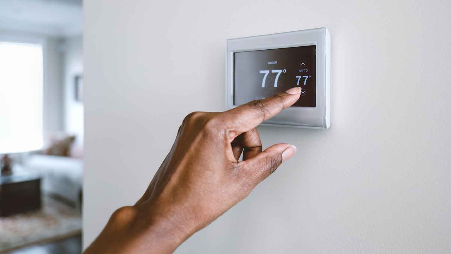 Closeup of a person adjusting a smart thermostat