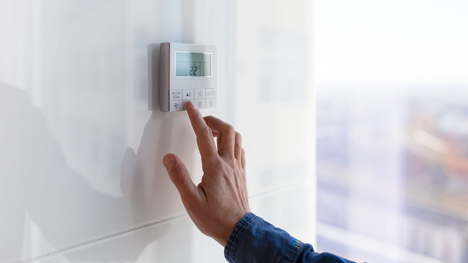 Closeup of a man adjusting temperature on a thermostat