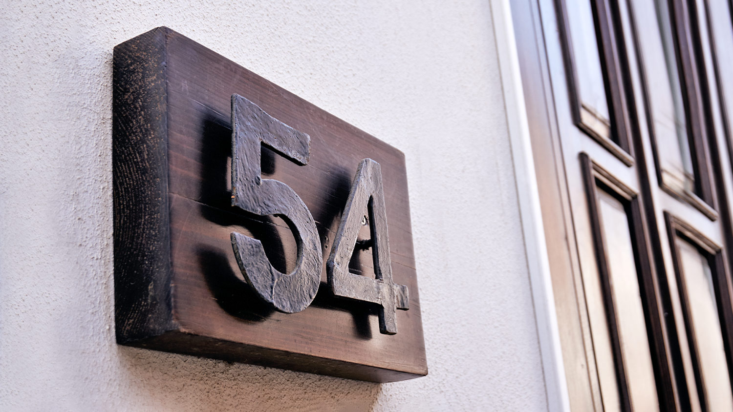 #54 house number on wood block next to door