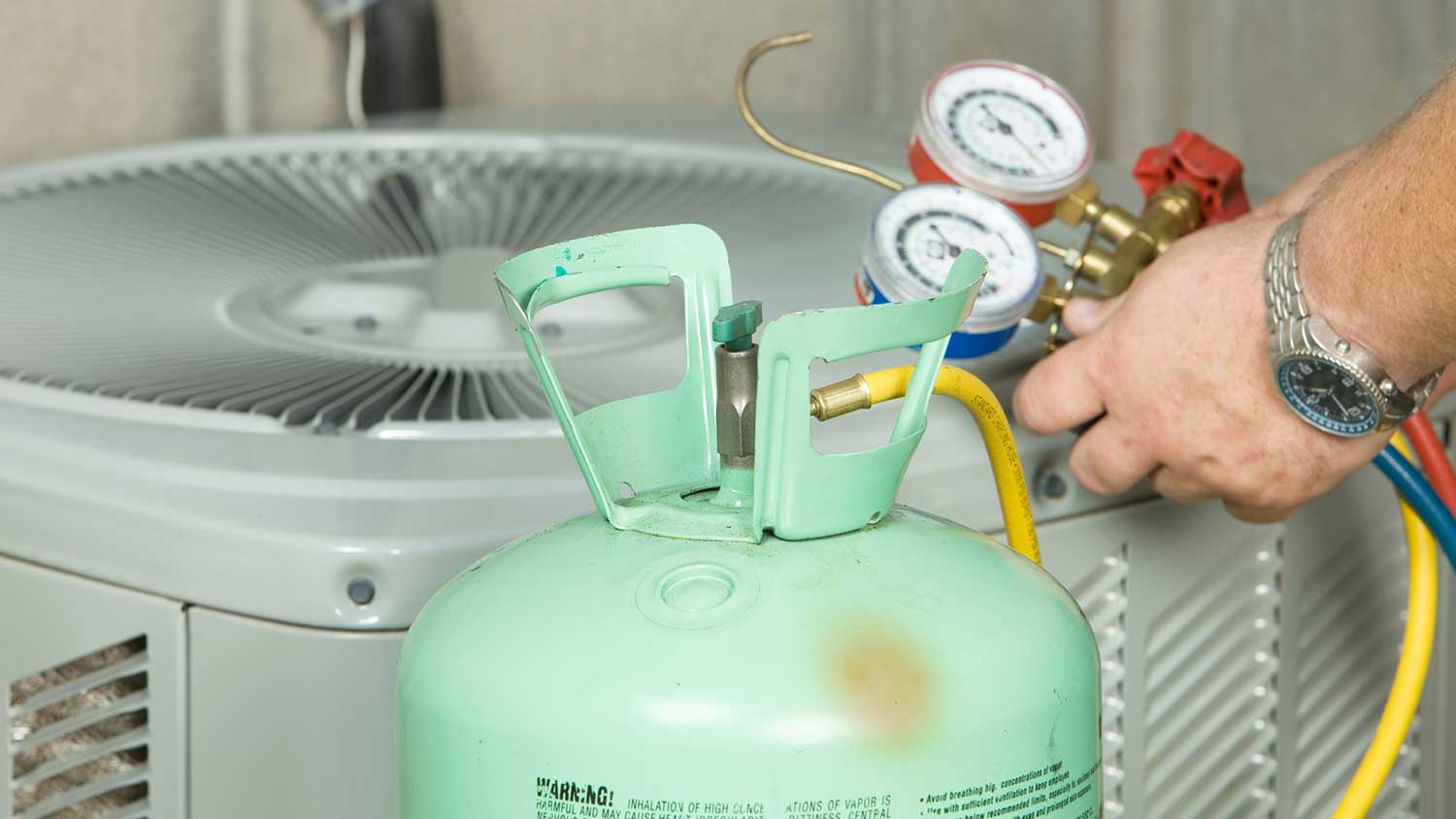 Technician adding air conditioning refrigerant to an AC unit