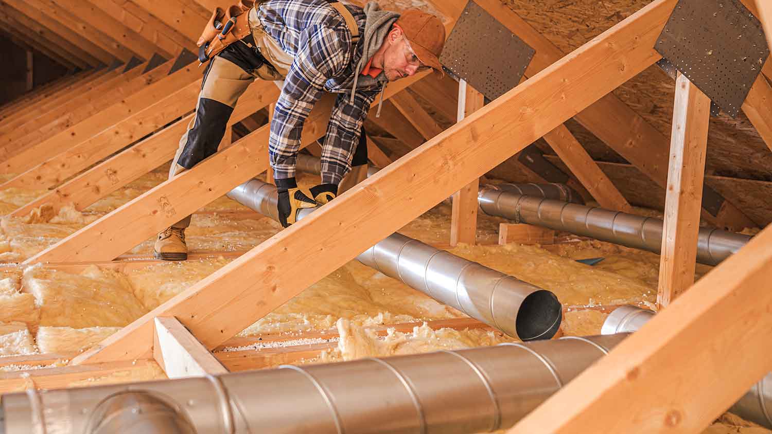 HVAC professional installing air ducts in the attic