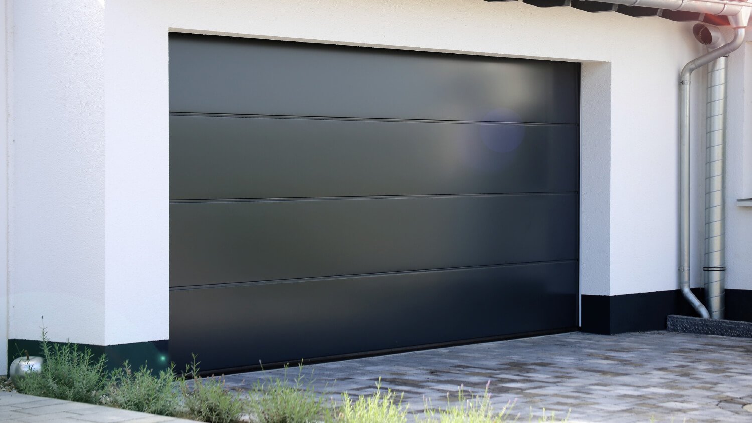 dark aluminum garage door next to plants