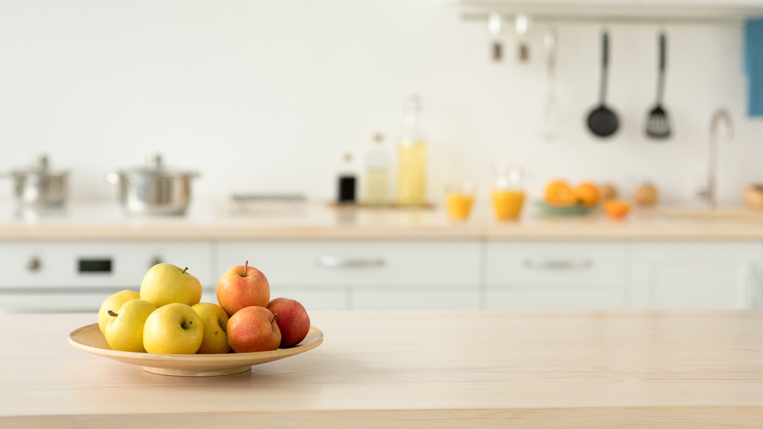 Apples placed in a wooden bowl on a kitchen countertop