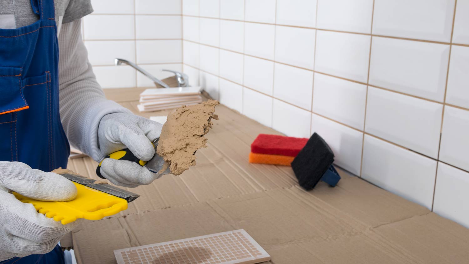 man applying grout to wall tiles