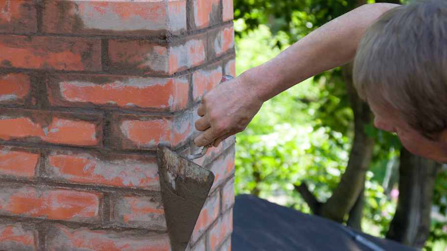 man apply mortar to chimney