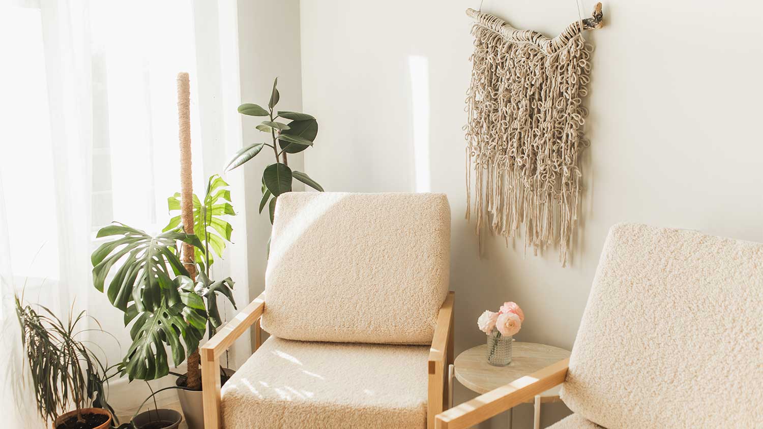 A room with armchairs and macrame wall hanging