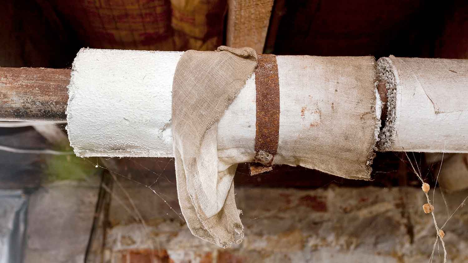 Basement plumbing pipes wrapped in asbestos insulation