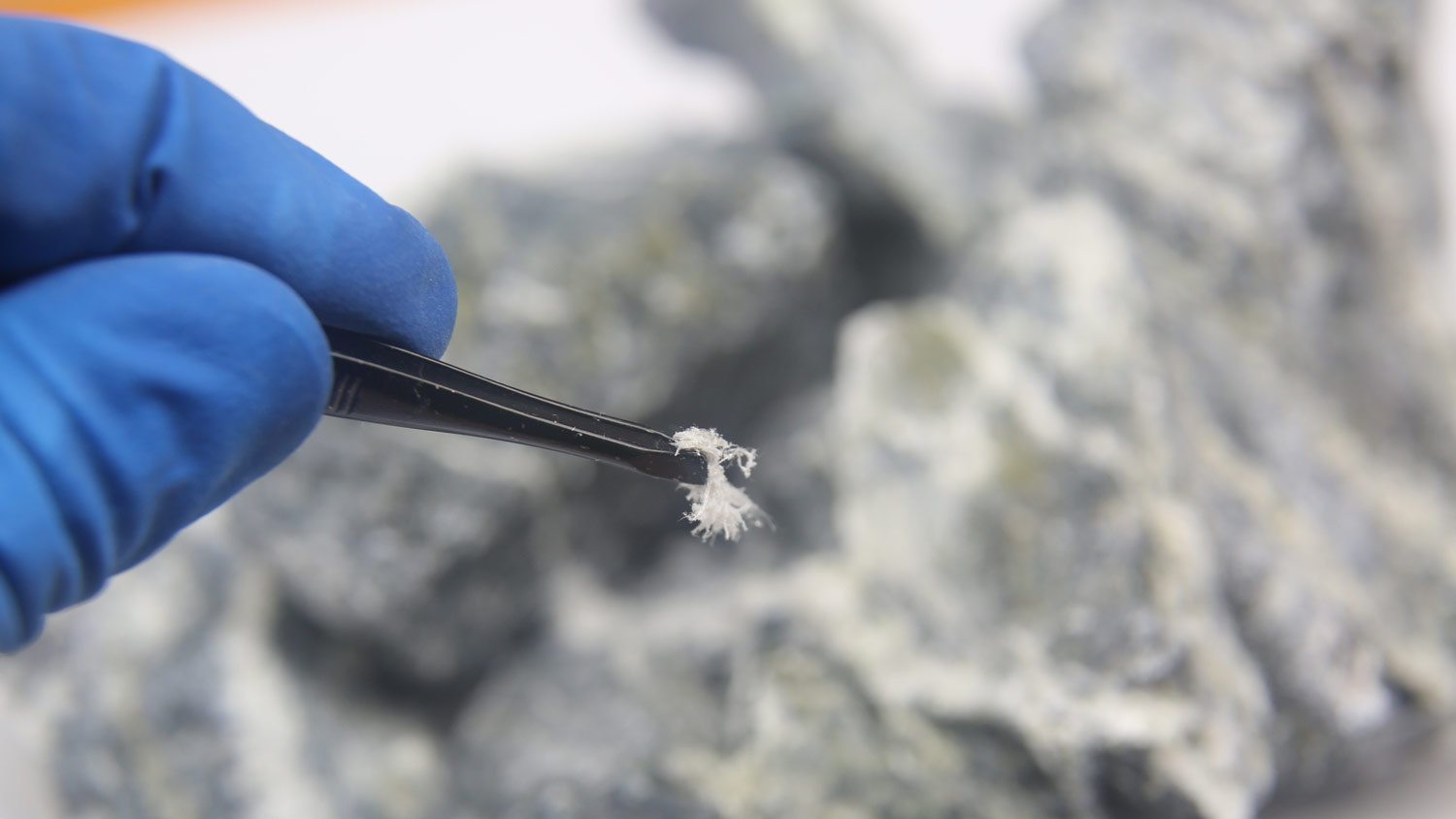 close up of asbestos fiber being held by tweezer 