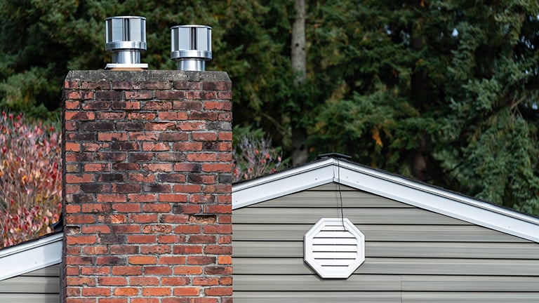 The exterior wall of a house with an attic fan