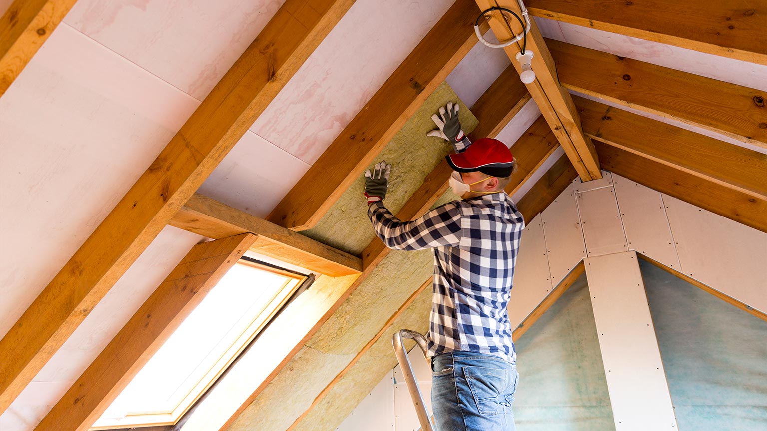 Man installing thermal roof insulation layer in attic