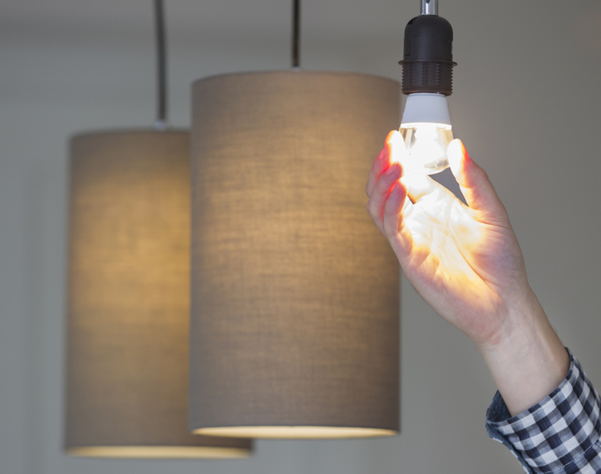 man screwing in light bulb in hanging lamp