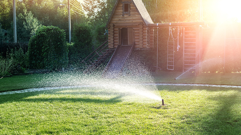 An automatic lawn watering system in full action on a sunny day